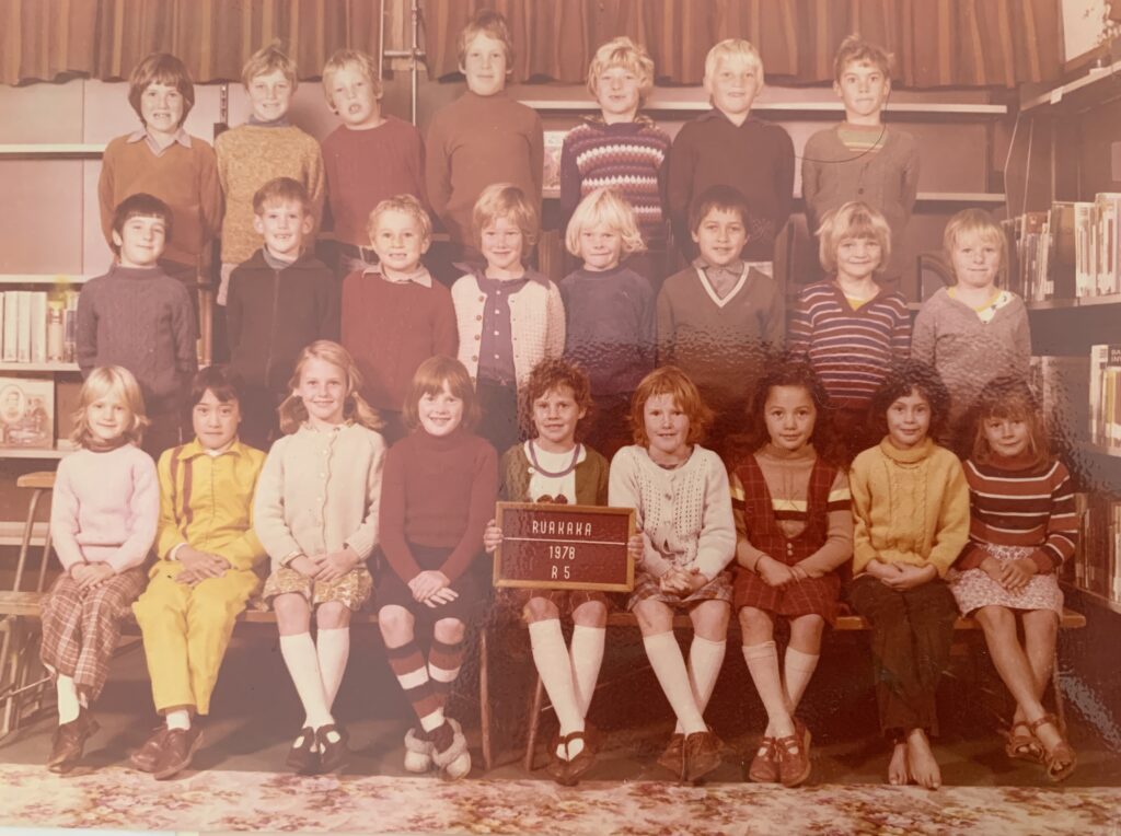 A group of young students standing in three rows looking at the camera. One student is holding a sign that reads: Ruakaka 1978 R5