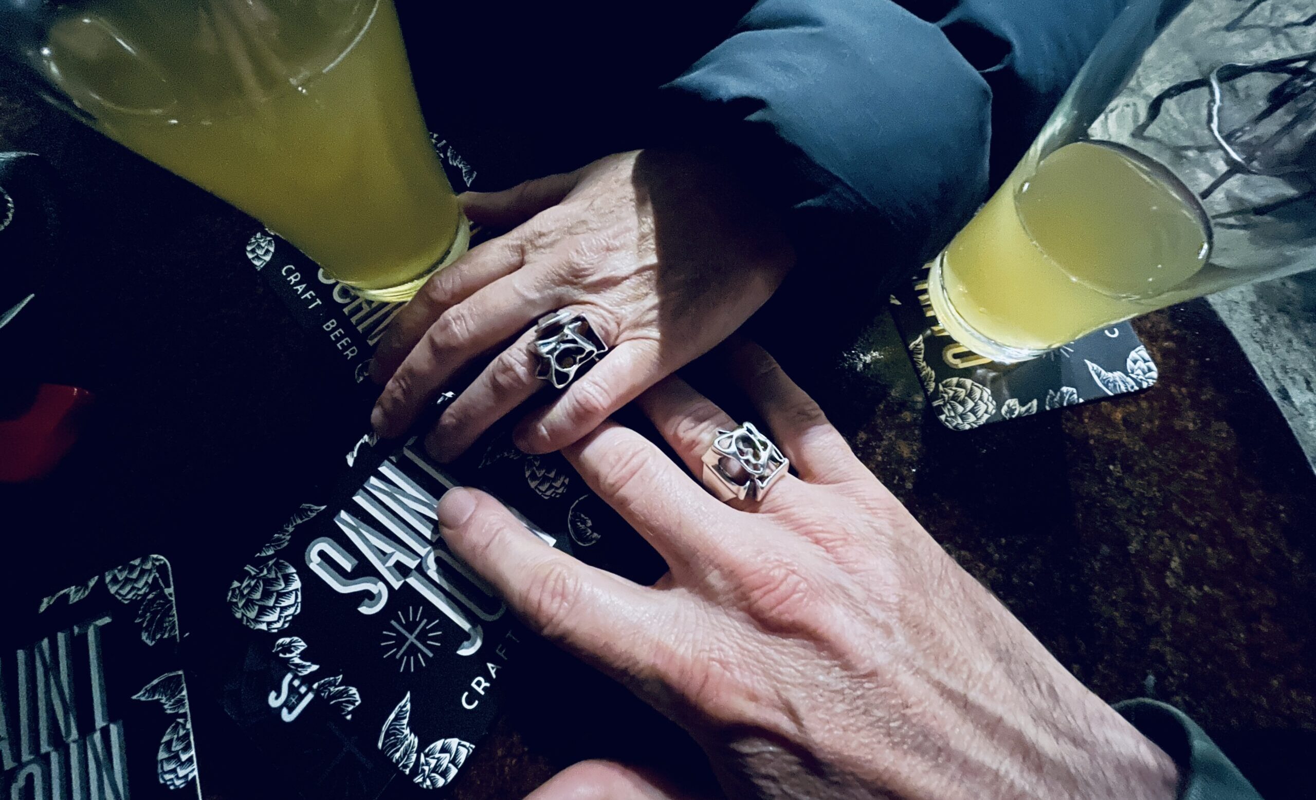 two different adult hands, holding. they both have the same silver ring.